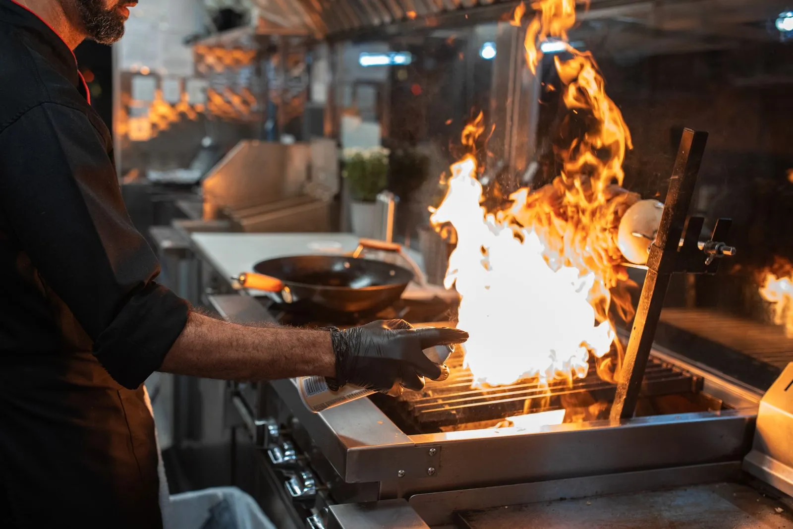 Un chef saisit une viande au-dessus de grandes flammes