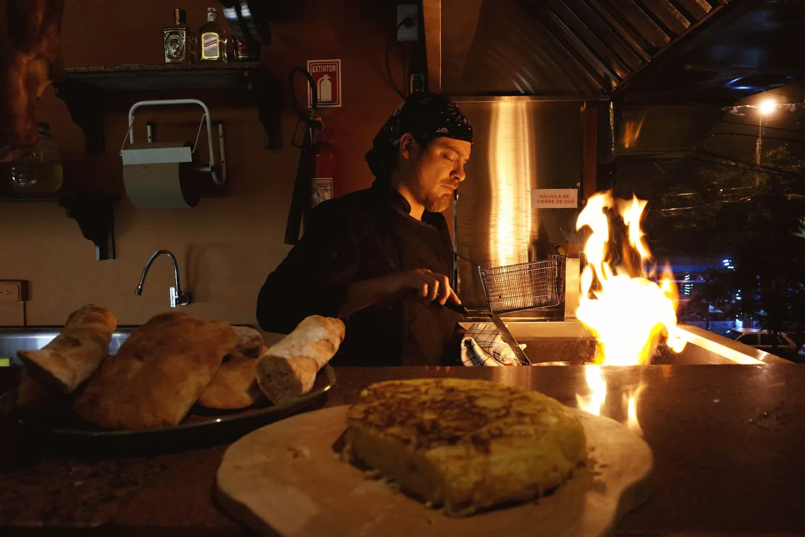 Un cuisinier prépare des plats près d’un feu de bois